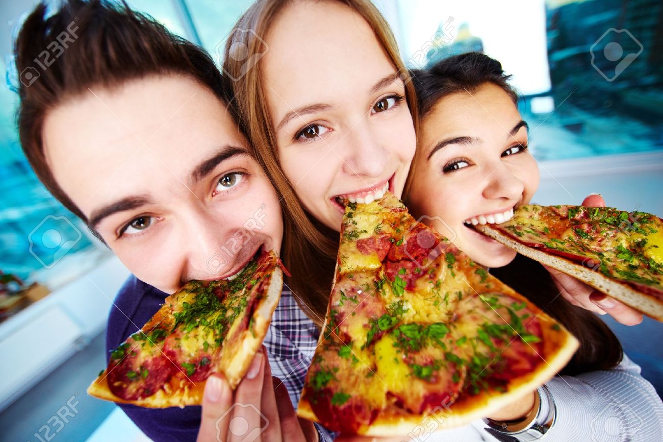 Image-of-happy-teenage-friends-eating-pizza-and-looking-at-camera