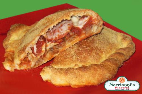 An image of a "build your own" calzone, it's cut in half to expose the beautifully baked center. of pepperoni, sausage, and mozzarella cheese it looks very delicious!!