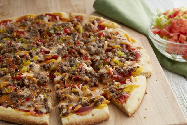 Another image of a Cheeseburger Pizza, it's baked and has toppings of hamburger meat, tomatoes, lettuce cheddar and mozzarella cheeses, it looks very good!